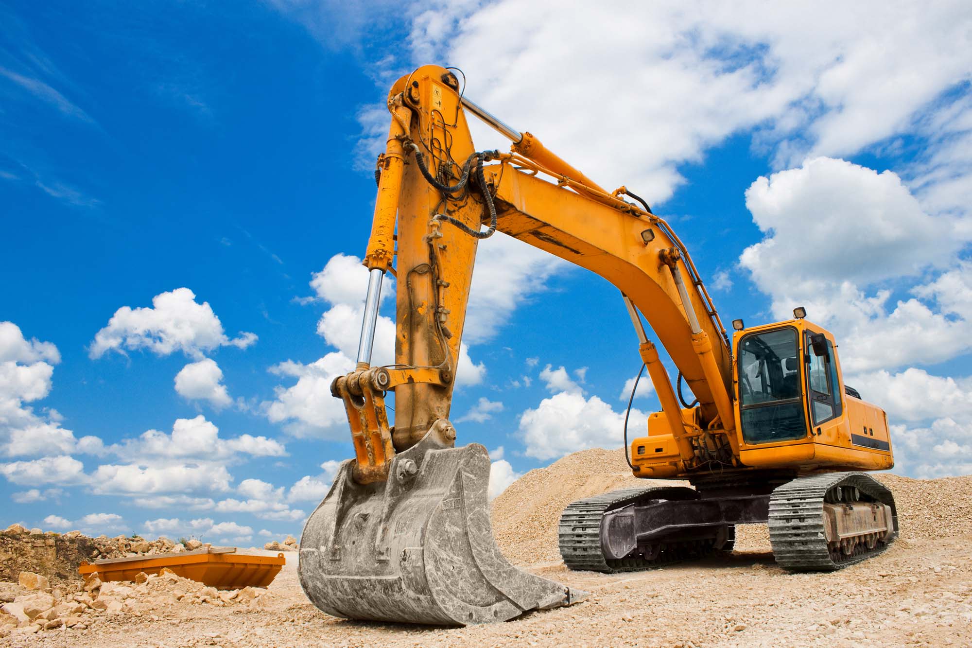 Yellow excavator on a construction site against blue sky